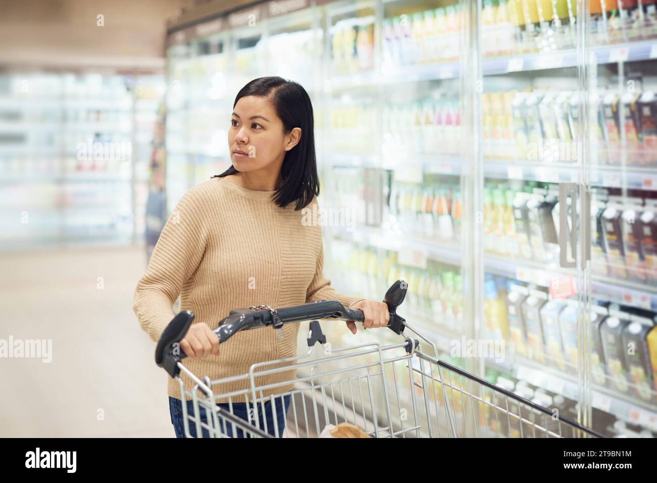 Donna in un supermercato di fronte al frigo Foto Stock