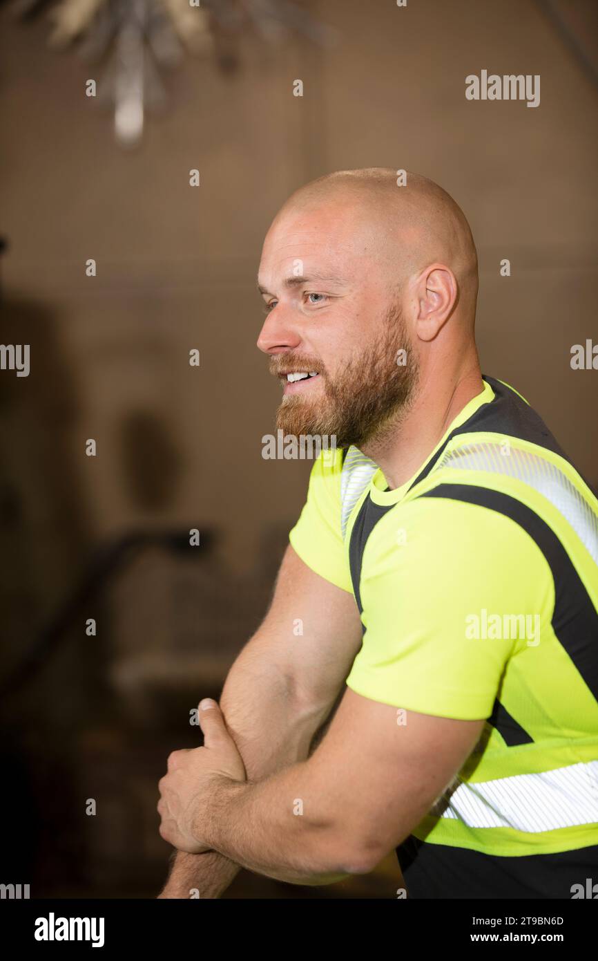 Lavoratore maschio sorridente in abiti riflettenti Foto Stock