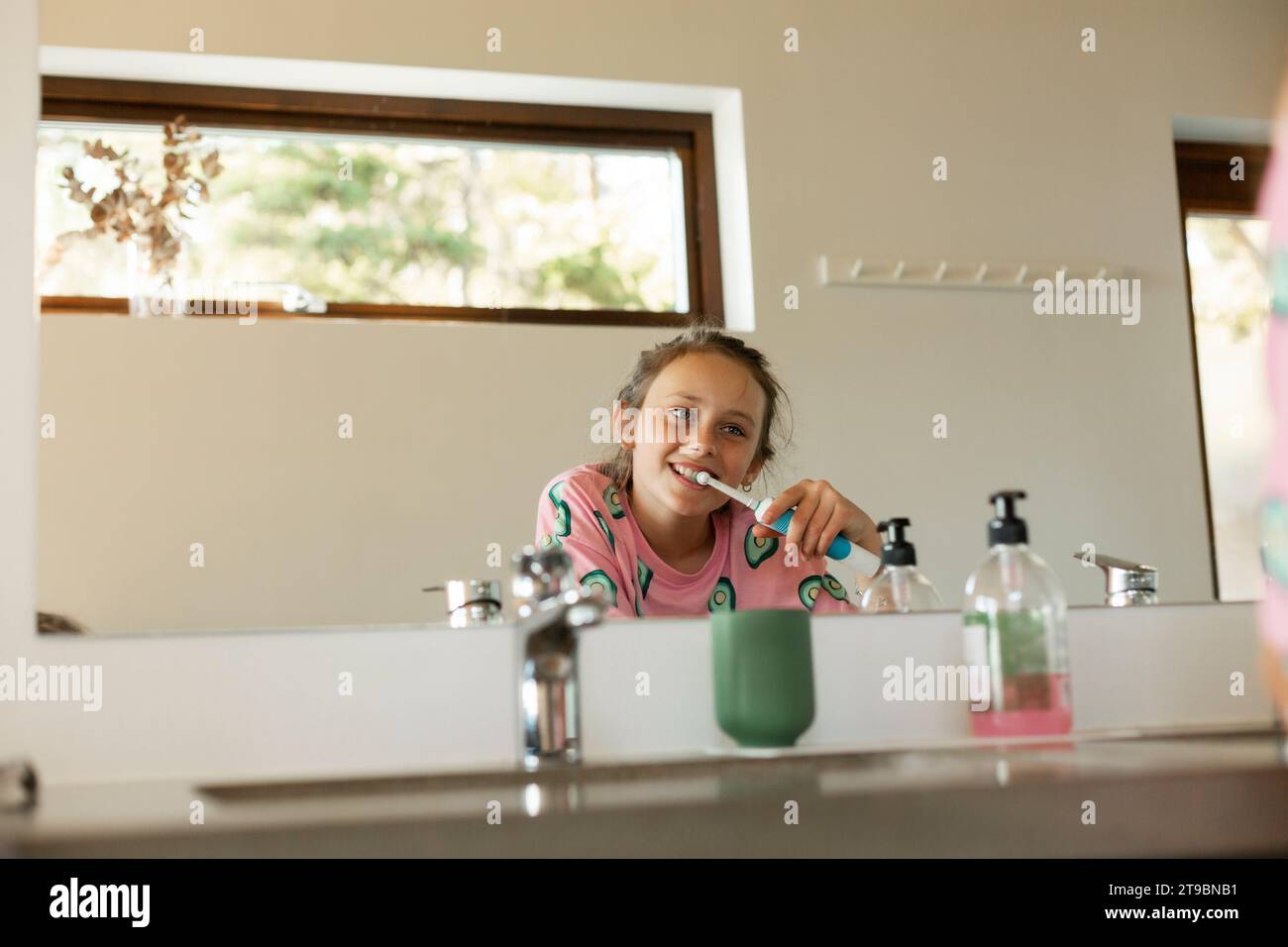 Ragazza che pulisce i denti riflettendo lo specchio del bagno Foto Stock
