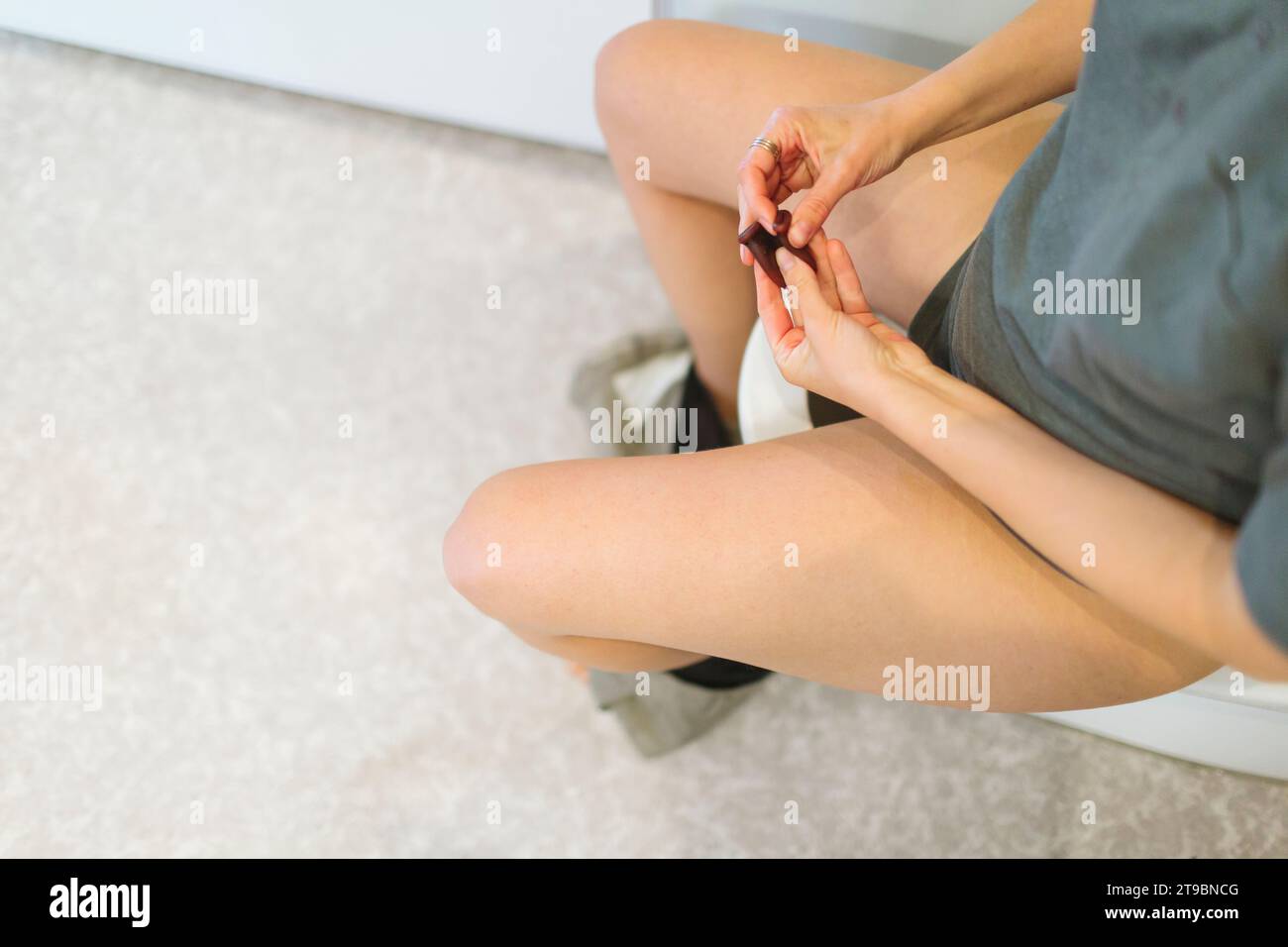 Donna che usa una coppetta mestruale in bagno Foto Stock