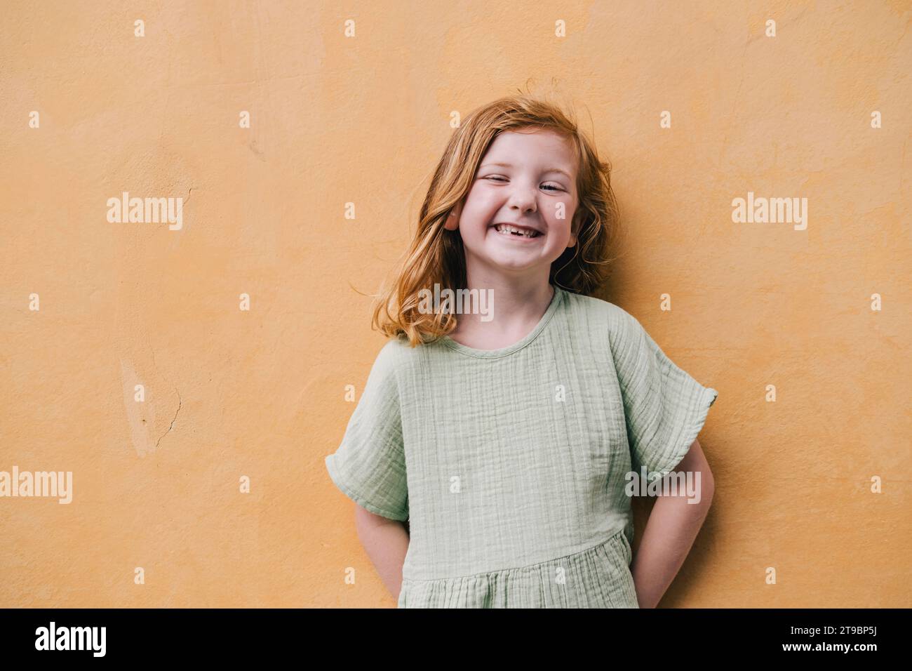 Ragazza dai capelli rossi che sorride contro il muro Foto Stock