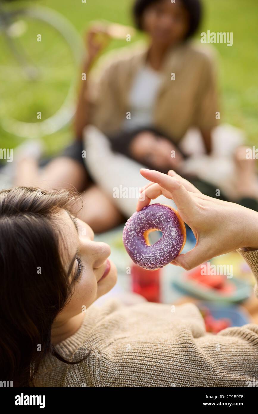 Ragazza adolescente che mangia ciambella al picnic Foto Stock