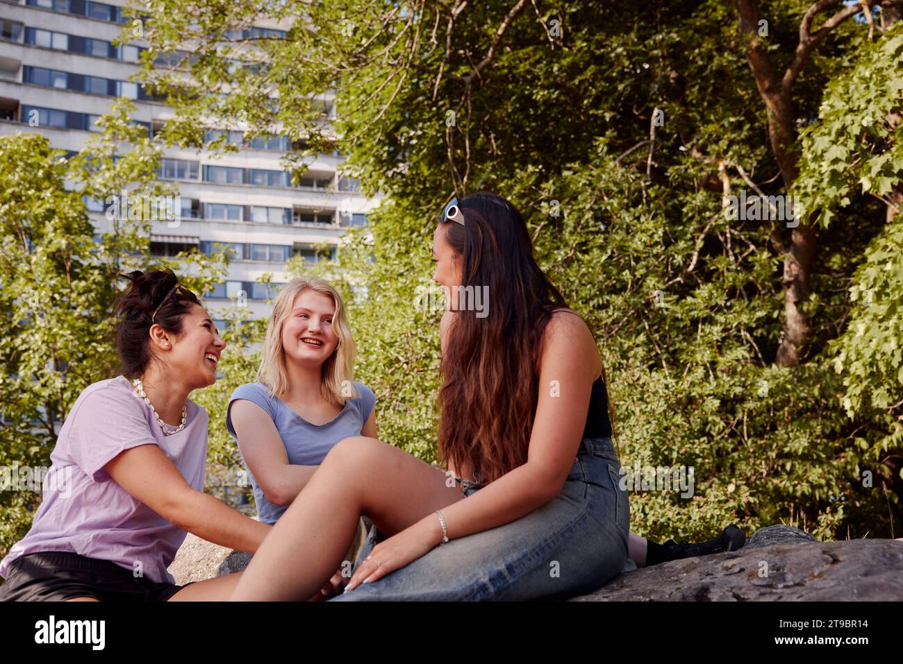 Tre giovani amiche sedute insieme a parlare Foto Stock