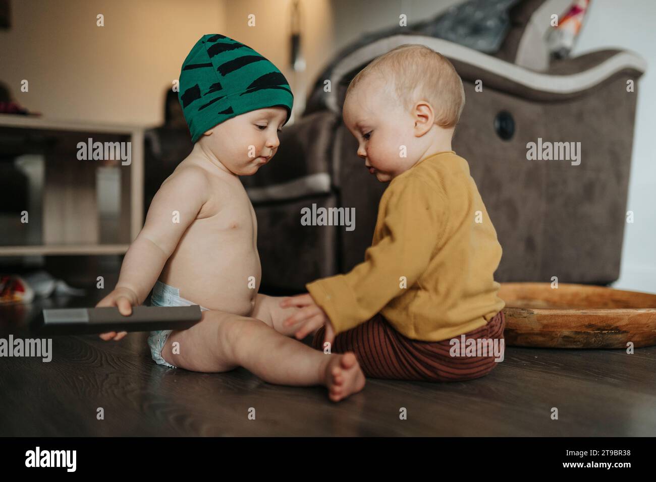Bimbi gemelli seduti insieme sul pavimento Foto Stock