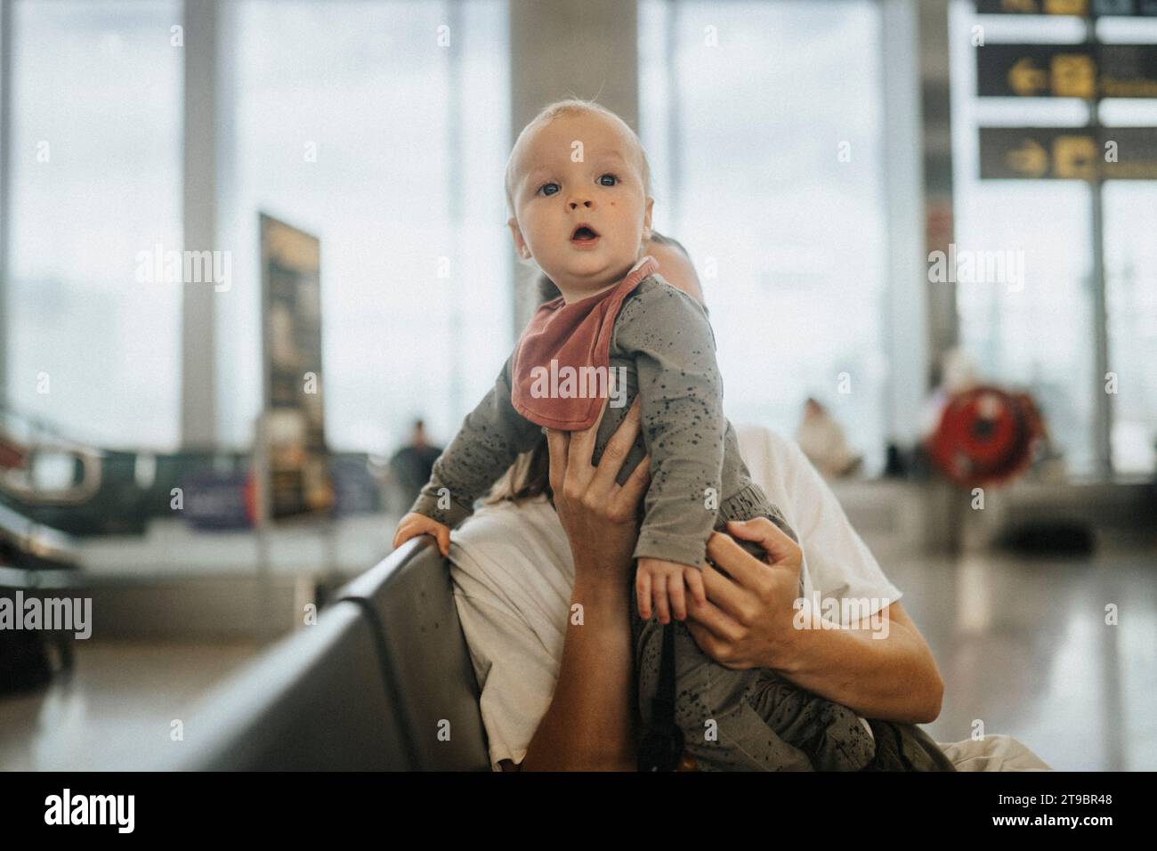 Madre con bambino che aspetta all'aeroporto Foto Stock