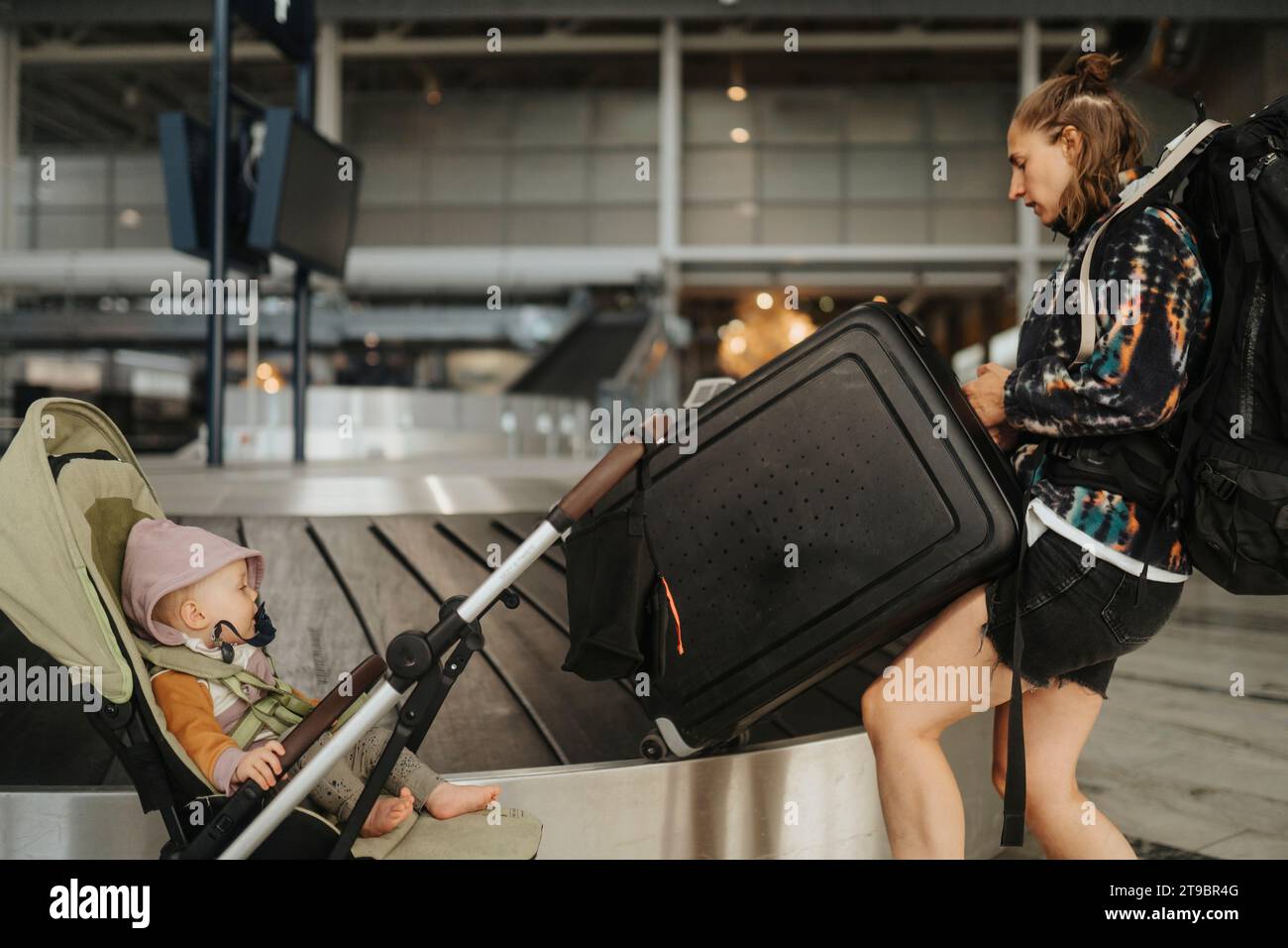 Madre con bambino che raccoglie i bagagli all'aeroporto Foto Stock