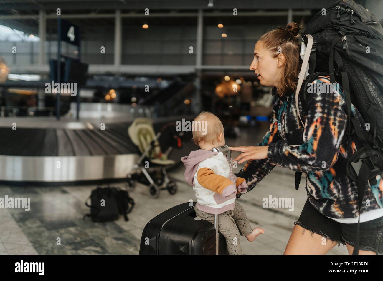 Madre con bambino che raccoglie i bagagli all'aeroporto Foto Stock
