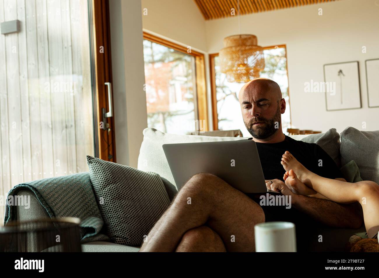 Uomo maturo che utilizza un notebook mentre lavora da casa in salotto Foto Stock