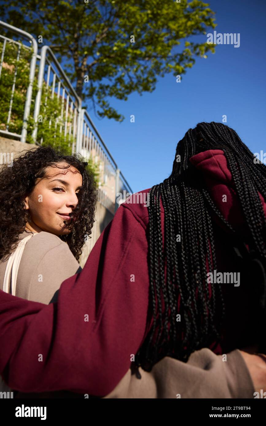 Ritratto ad angolo basso di una giovane donna sorridente con un braccio intorno a un'amica Foto Stock