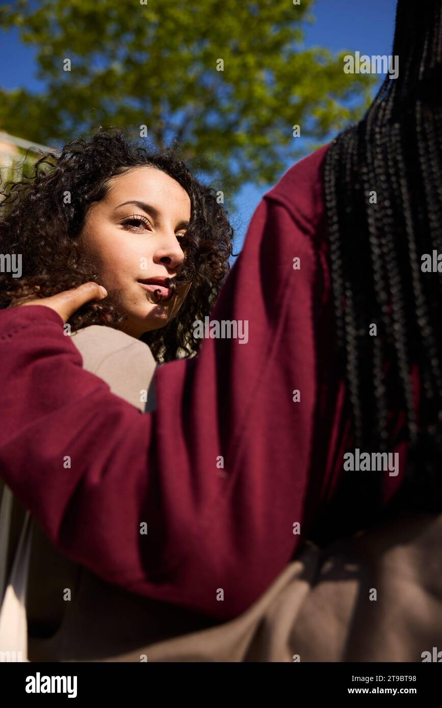 Vista angolare bassa di una giovane donna con un braccio intorno a un'amica Foto Stock