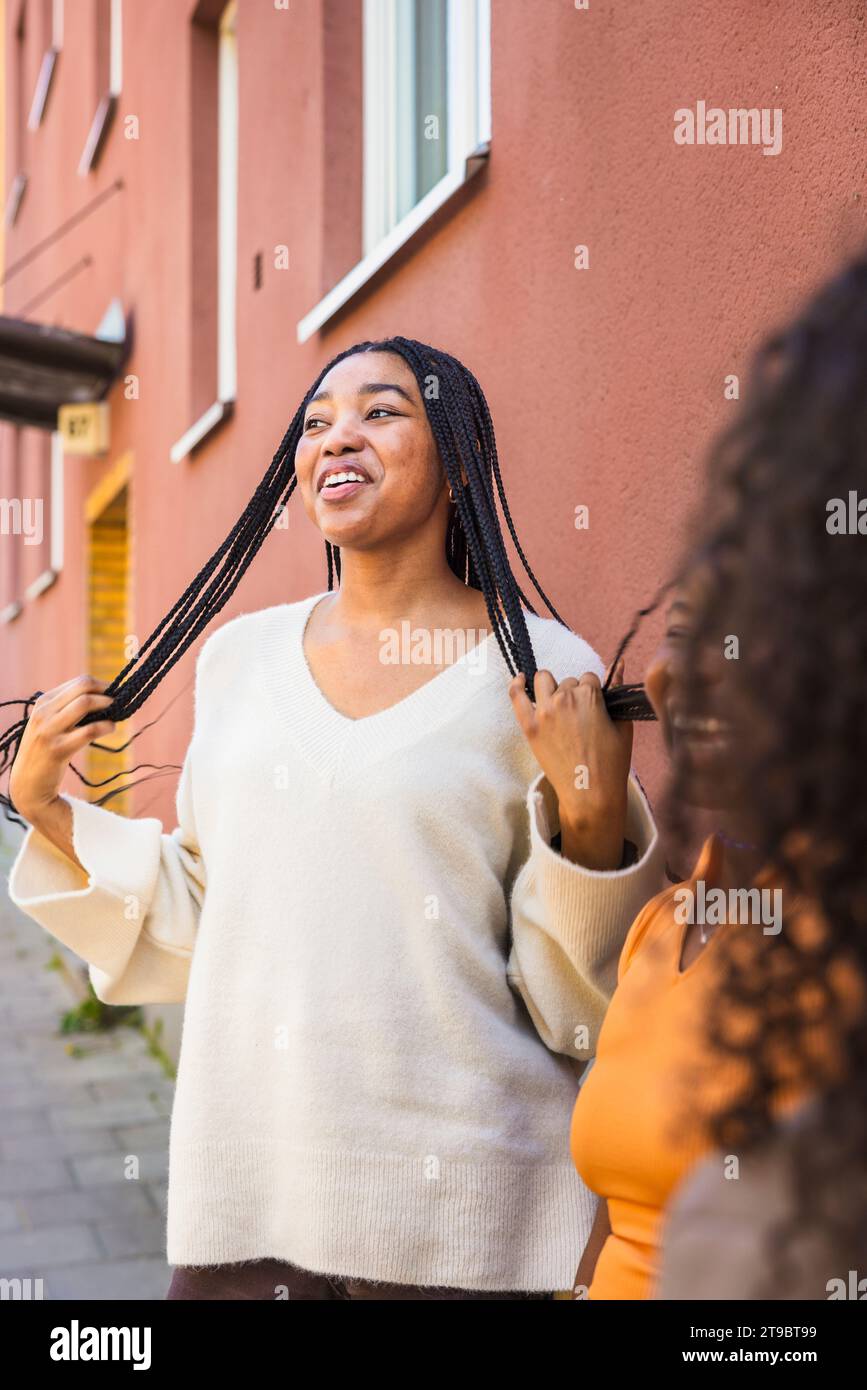 Donna felice con le mani nei capelli in piedi da amiche femminili sul sentiero Foto Stock