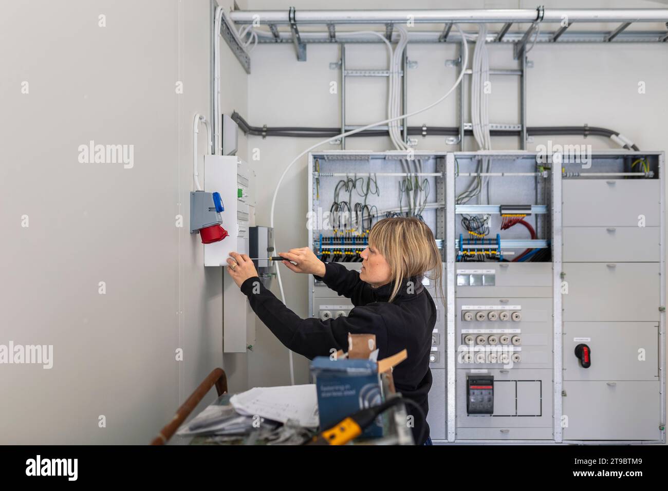 Tecnico donna che installa la scatola fusibili nella sala di controllo del settore industriale Foto Stock