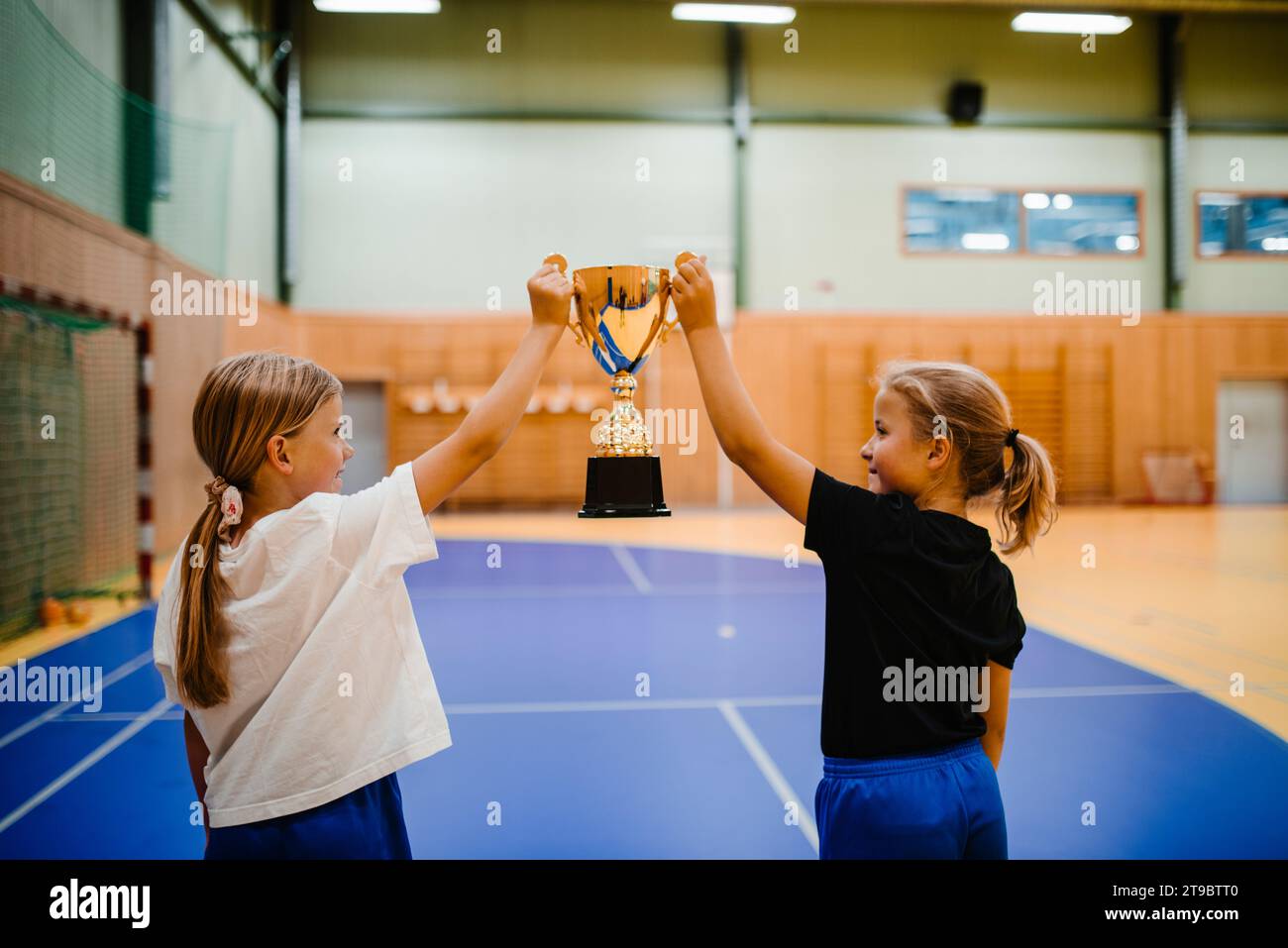 Vista posteriore delle giocatrici con trofeo in piedi sul campo sportivo Foto Stock