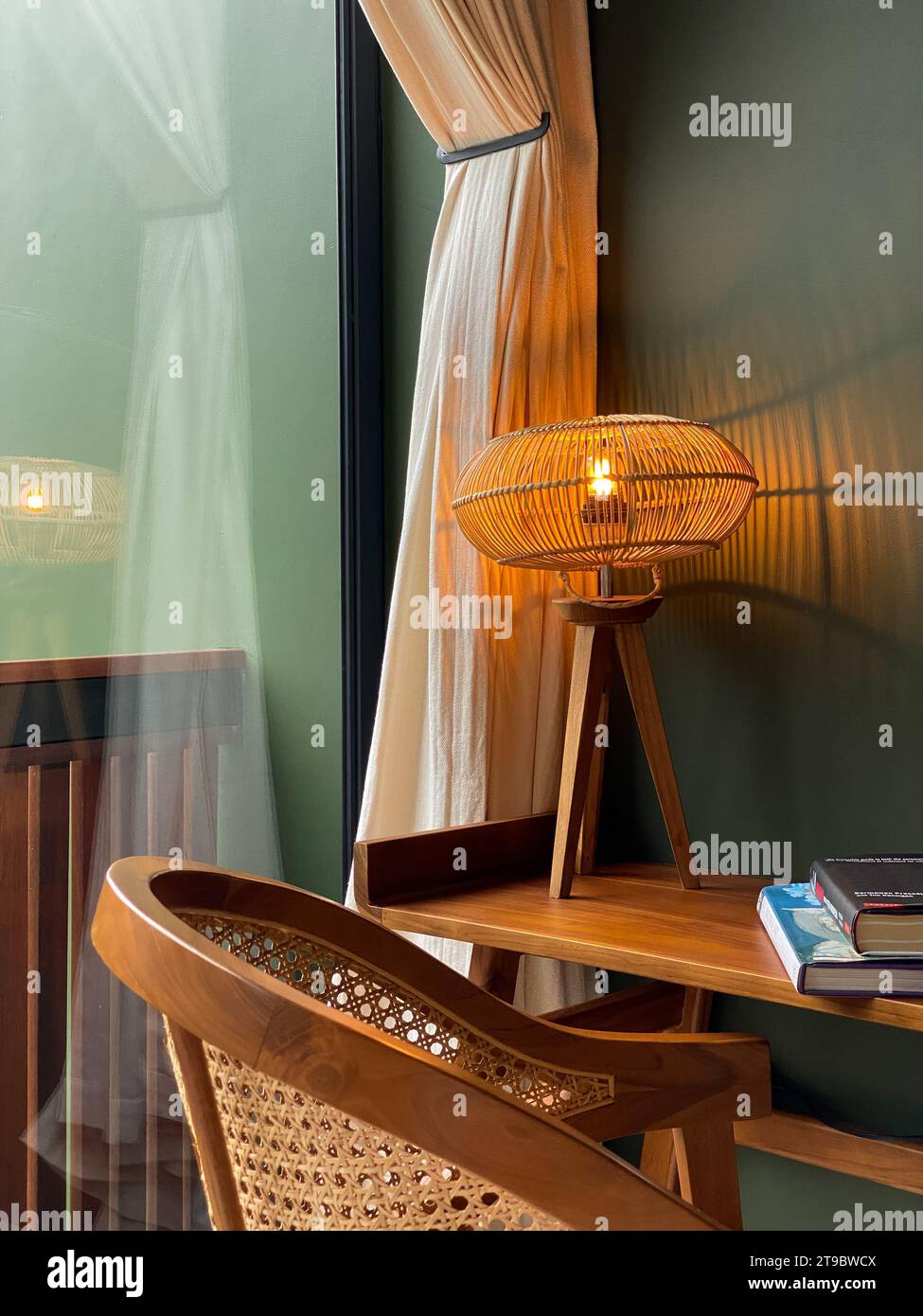 Lampada da tavolo con paralume in rattan su tavolo in legno con primo piano sedia in rattan Foto Stock