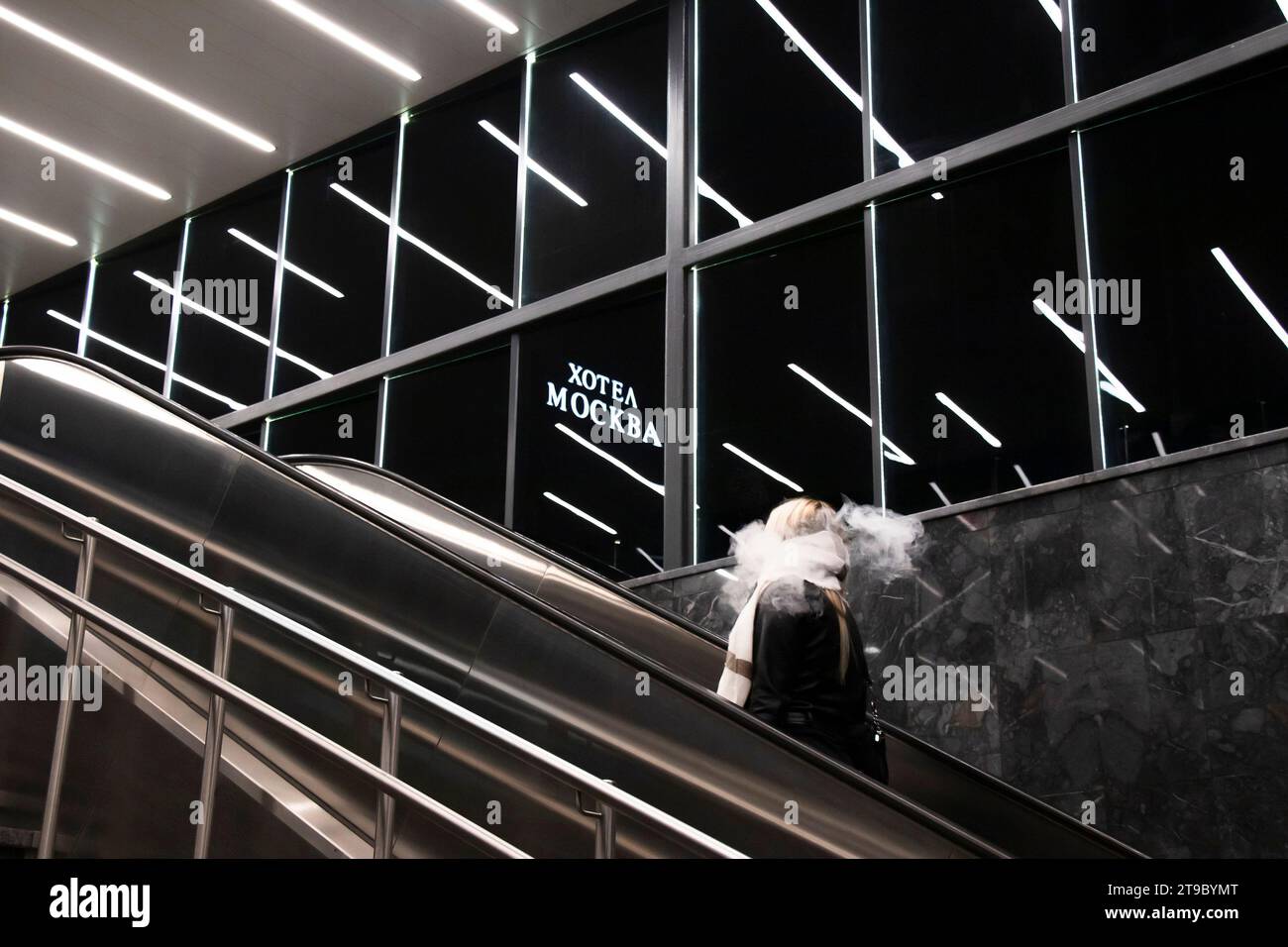 Belgrado, Serbia - 20 novembre 2023: Persona che sale sulla scala mobile della metropolitana, con luci interne riflettenti e cartello dell'hotel Mosca in caratteri cirillici Foto Stock