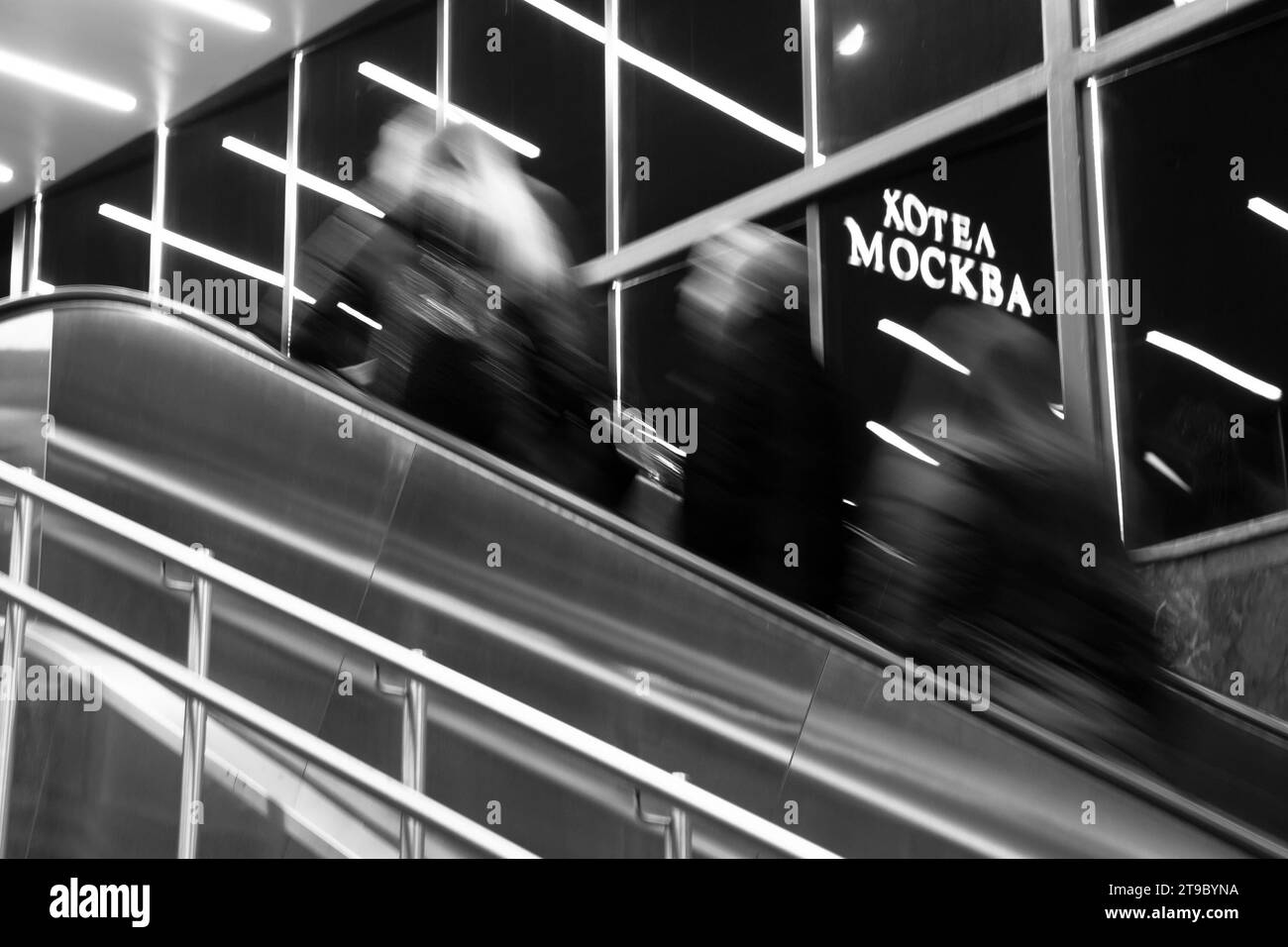 Belgrado, Serbia - 20 novembre 2023: Persone astratte sfocate che salgono le scale della metropolitana con riflessi di luci interne e l'insegna dell'hotel Mosca a cirillo Foto Stock