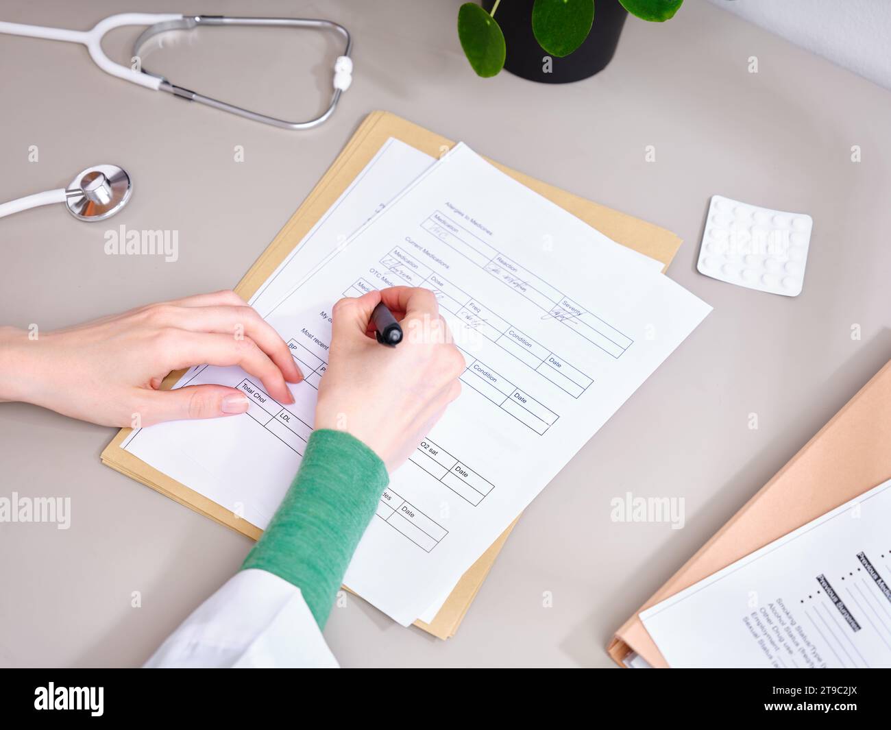 Vista dall'alto medico irriconoscibile prendere appunti nella documentazione medica presso la clinica Foto Stock