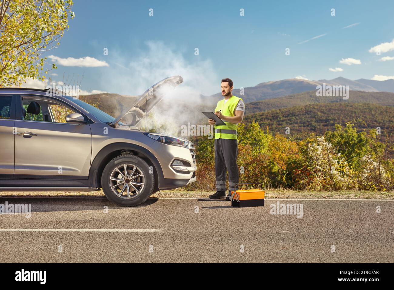 SUV su strada con cofano aperto e strada aiuta il lavoratore a scrivere un documento Foto Stock