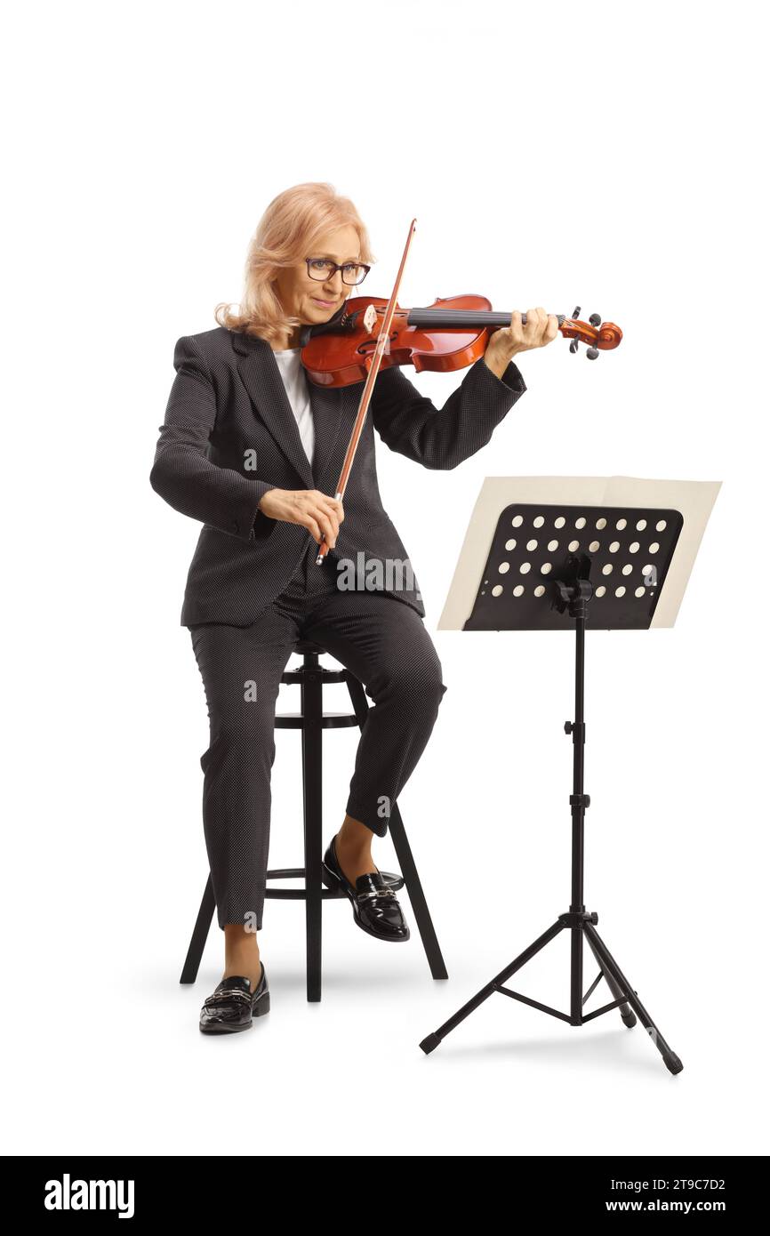 Ripresa completa di una donna matura su una sedia che suona un violino e legge un supporto musicale isolato su sfondo bianco Foto Stock