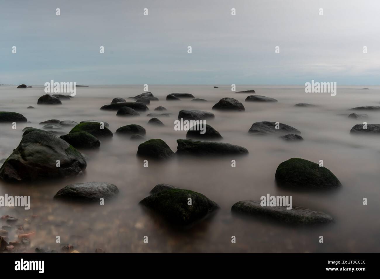 In mezzo alle profondità dell'inchiostro, la lunga esposizione svela la conversazione silenziosa tra pietre e mare, un balletto mistico sotto un velo di oscurità. Foto Stock