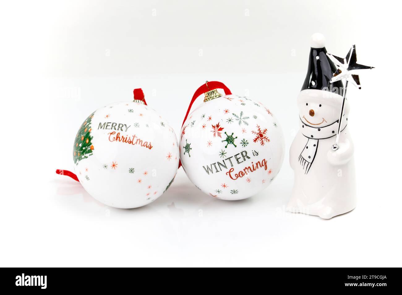 Due tradizionali palline bianche sull'albero di Natale e una figura con sciarpa, cappello a punta e una stella su un bastone Foto Stock
