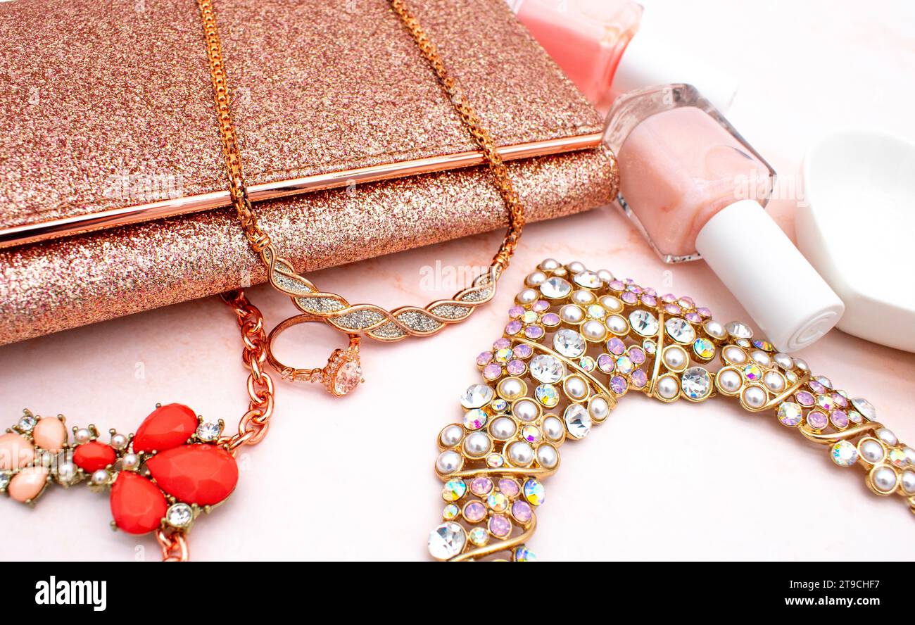 Stile e gioielleria a poggia piatta in oro rosa con sfondo al quarzo rosa, smalto per unghie rosa, pochette glitter e gioielli in diamanti oro rosa Foto Stock