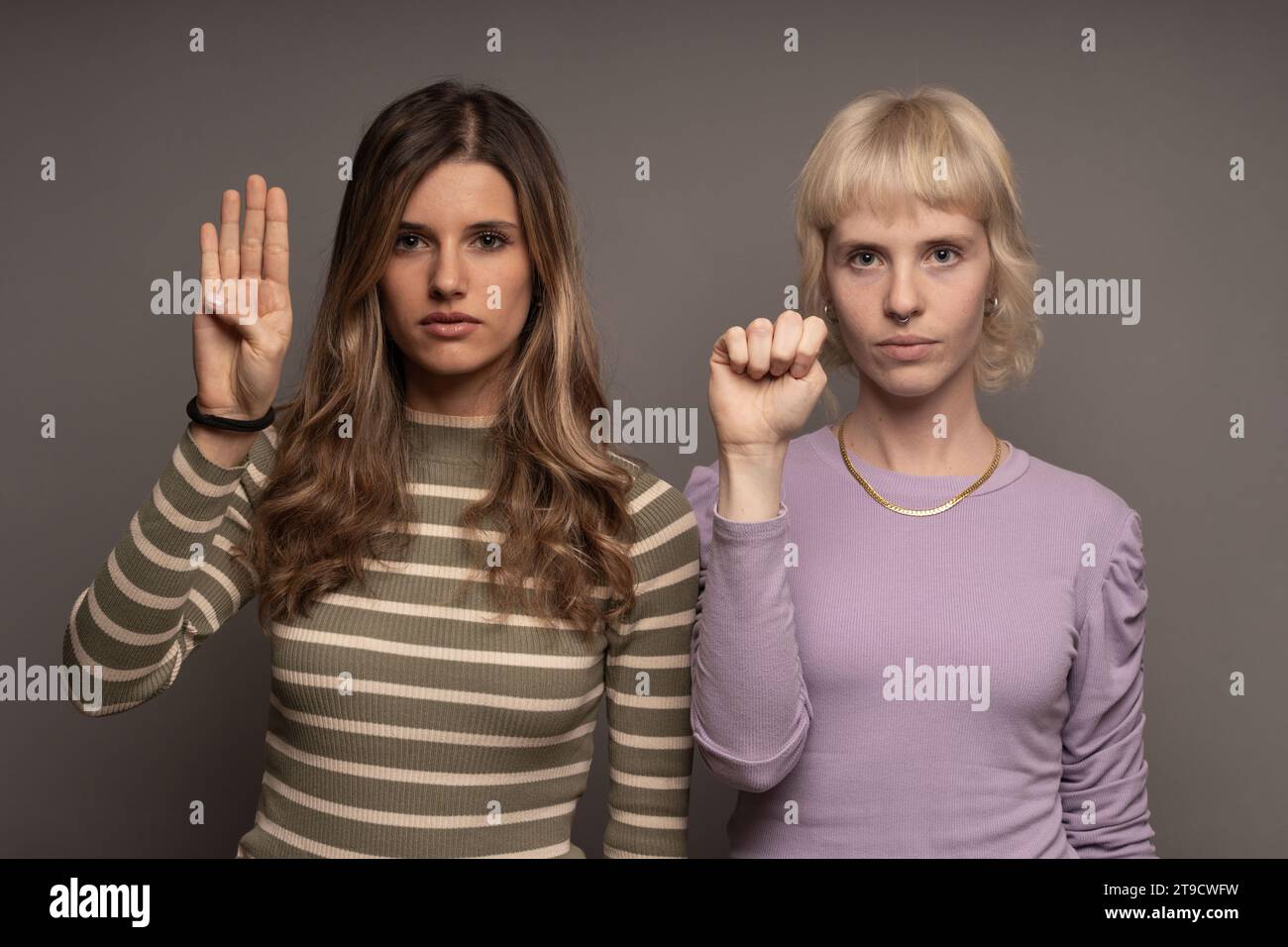 Due donne alzano la mano in un appello silenzioso, mostrando il segno SOS contro la violenza domestica, promuovendo la consapevolezza e il sostegno. Foto Stock