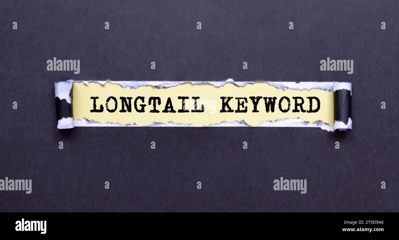 La mano di donna tiene un pezzo di carta con testo parola chiave a coda lunga sullo sfondo di grafici e blocco note. Foto Stock