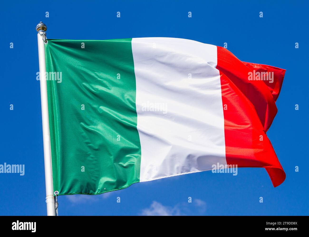 Bandiera d'Italia che sventola nel vento su palo contro il cielo con le nuvole nelle giornate di sole, primo piano Foto Stock