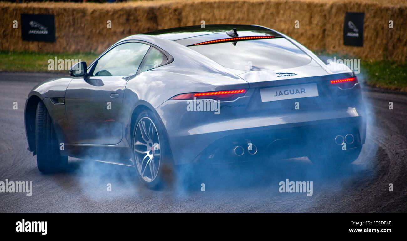 Auto sportiva Jaguar FType color argento in movimento con fumo di pneumatici su una strada asfaltata durante un display delle prestazioni Foto Stock