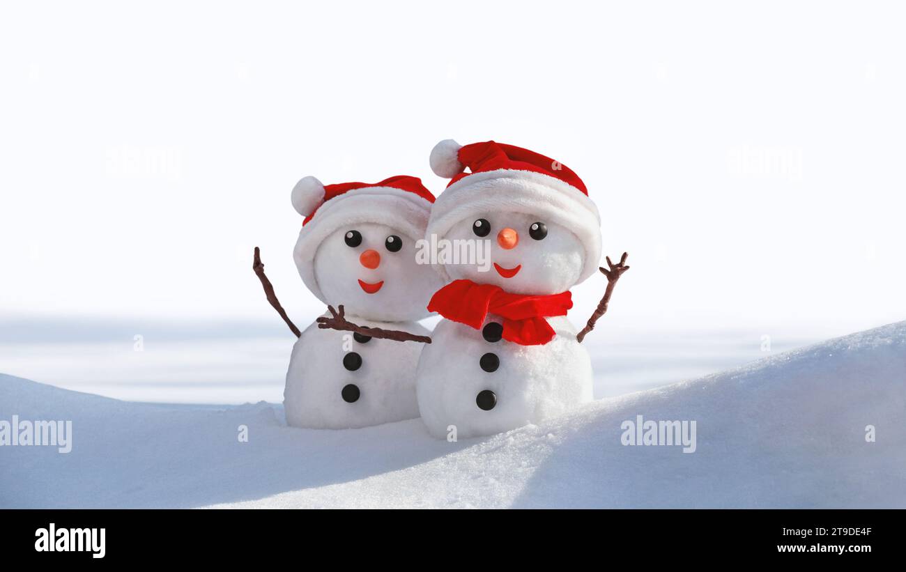 Vista di un paio di pupazzi di neve in un cappello di babbo natale sulla testa, isolato su sfondo bianco. Sfondo natalizio con spazio per la copia del testo Foto Stock