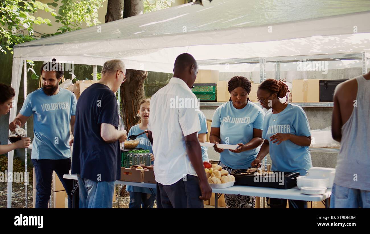 Volontari giovanili che contribuiscono ad alleviare la fame attraverso la fornitura di pasti caldi ai svantaggiati. Gli aiuti umanitari vengono forniti ai poveri, ai bisognosi e ai senzatetto. Foto Stock