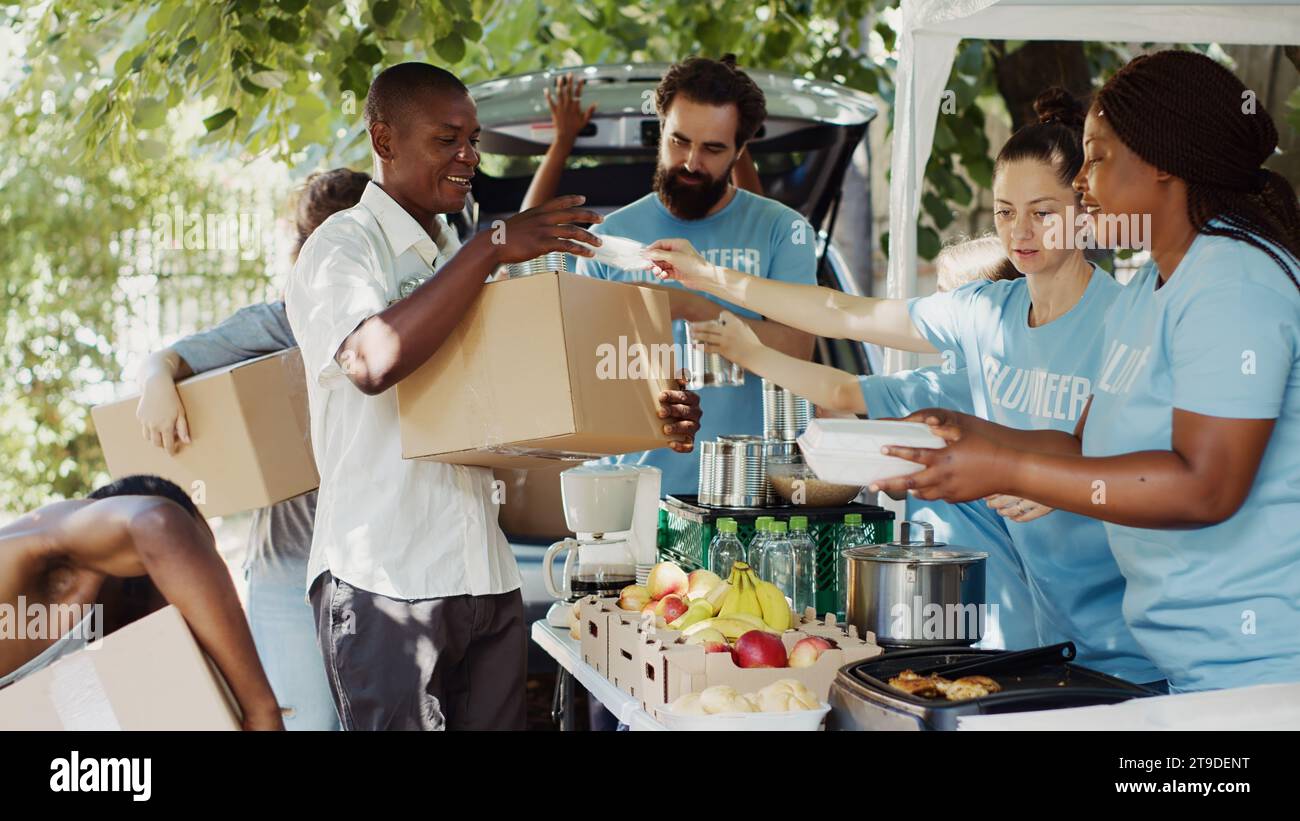 Gruppo di volontari che distribuiscono cibo confezionato ai bisognosi come gli anziani e i senzatetto. Il sincero gesto di gentilezza rende felici gli individui meno fortunati e allevia la loro sofferenza. Foto Stock