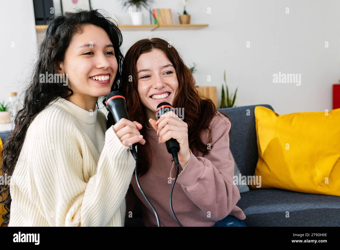 Donne amiche che si divertono a giocare al karaoke a casa Foto Stock