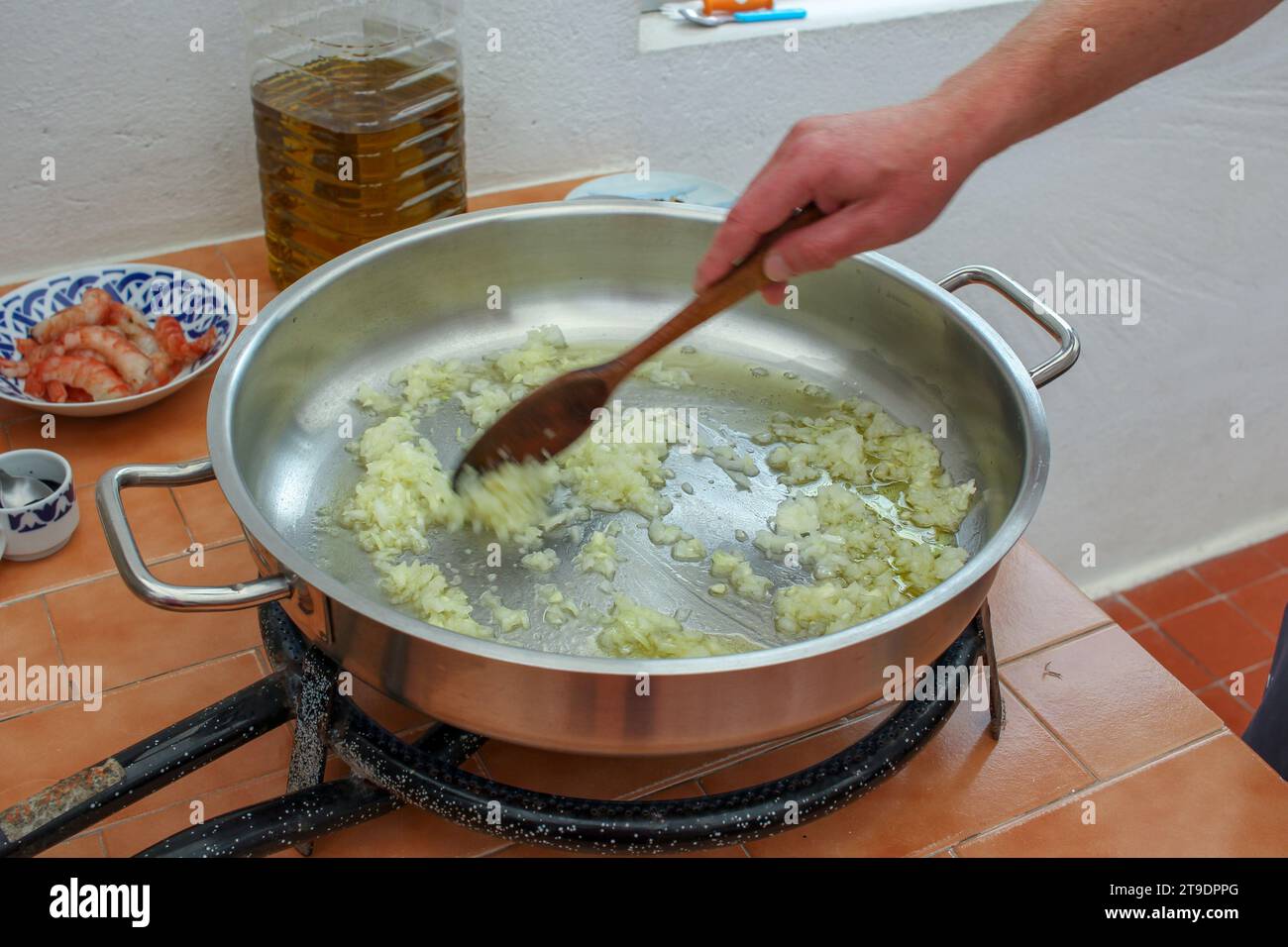 mescolare la cipolla con un cucchiaio di legno in una padella con olio d'oliva Foto Stock