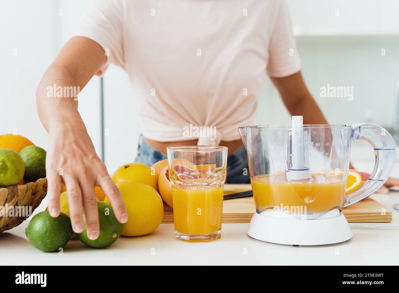 Bicchiere di succo d'arancia e spremiagrumi sul tavolo bianco della cucina Foto Stock