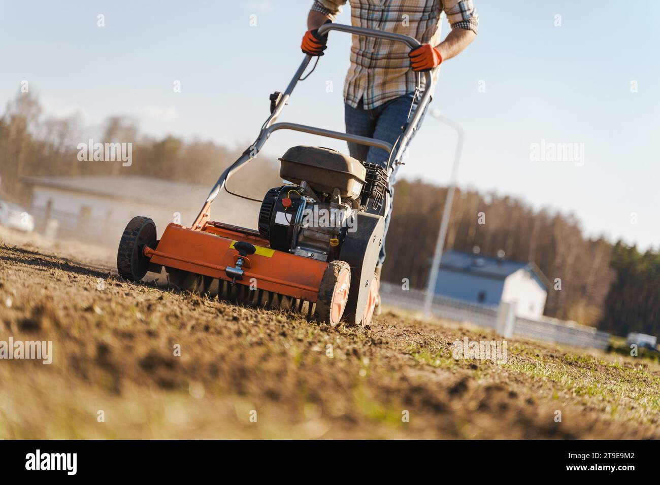 Giovane che utilizza una macchina per aerazione per scarificare e aerare prati o prati Foto Stock