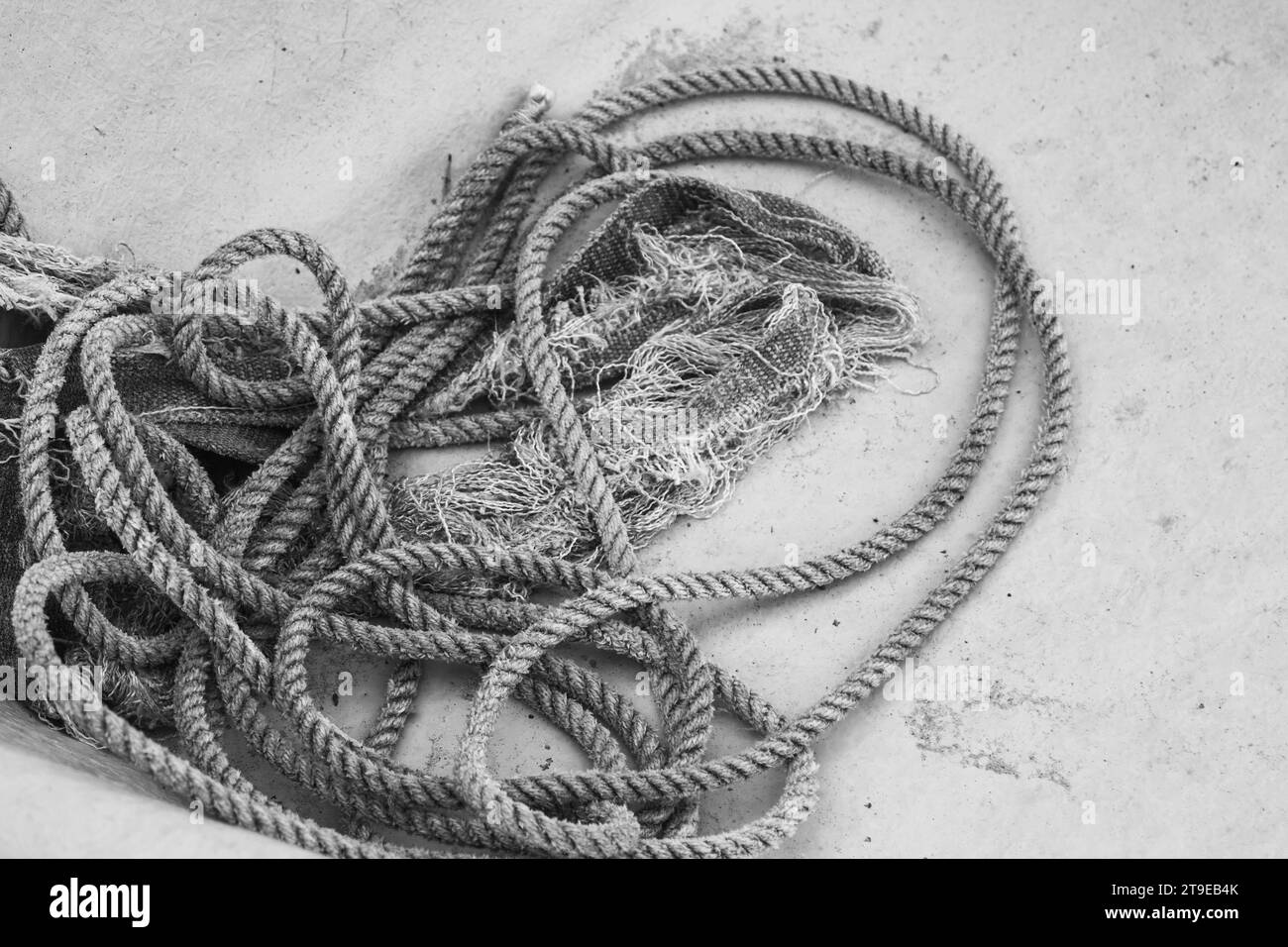 Primo piano in bianco e nero di una spirale di corda nautica aggrovigliata sul fondo dello scafo di un peschereccio. Foto Stock