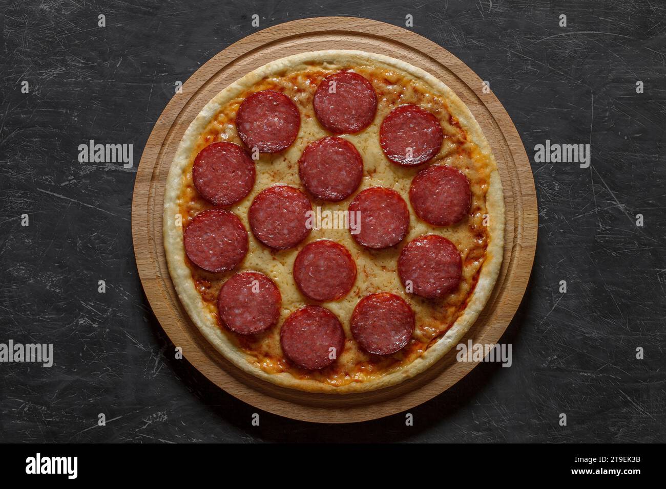 Pizza al peperoni con salsiccia, intera non tagliata, vista dall'alto sfondo scuro. Foto Stock