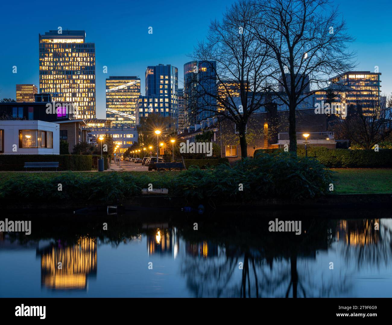 Quartiere degli affari di Amsterdam Zuidas la sera, moderni edifici per uffici che si riflettono nel canale zuider amstel Foto Stock