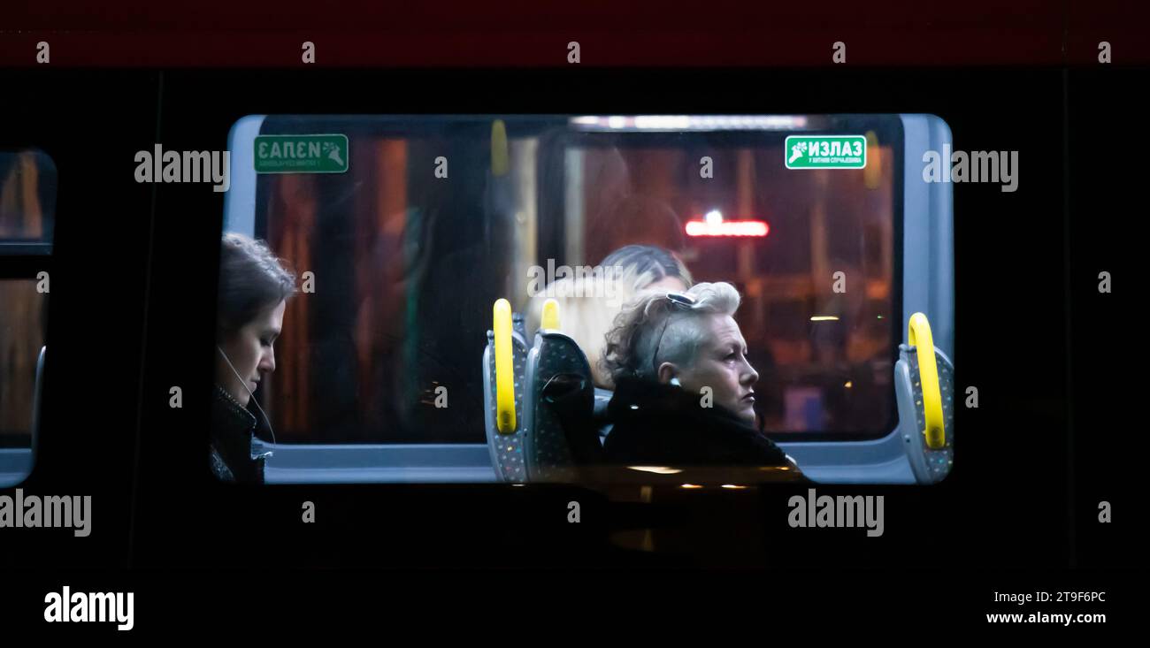 Belgrado, Serbia - 23 novembre 2023: Passeggeri donne seduti sul finestrino mentre viaggiano in un autobus cittadino di notte Foto Stock