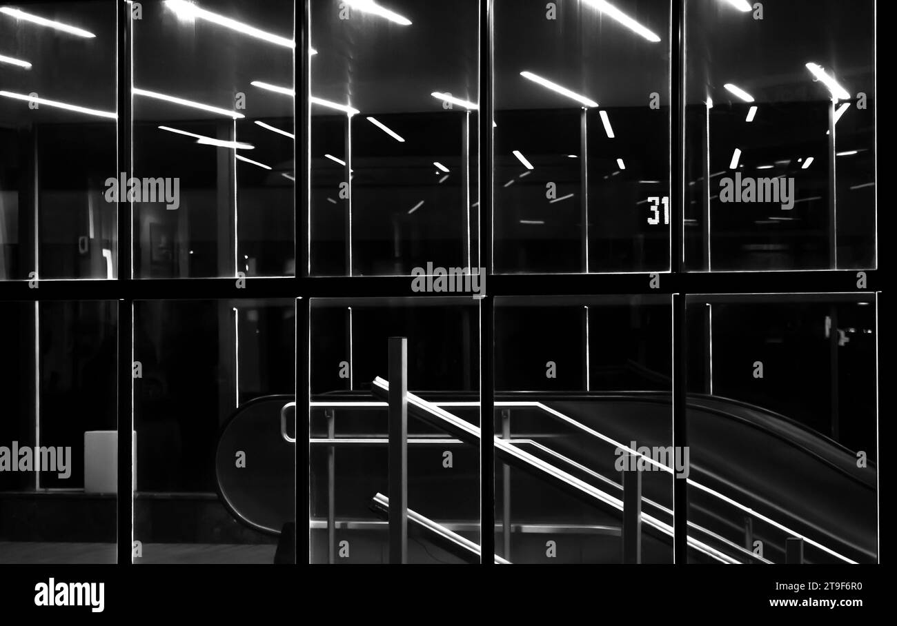 Ingresso in vetro illuminato della passerella sotterranea della città con scale e scale mobili di notte Foto Stock