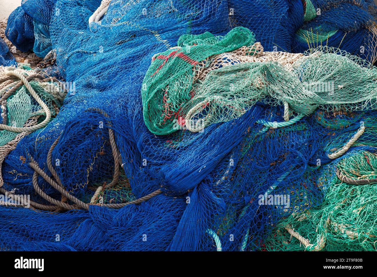 Rete da pesca in nylon blu e verde nel porto. Industria della pesca commerciale Foto Stock