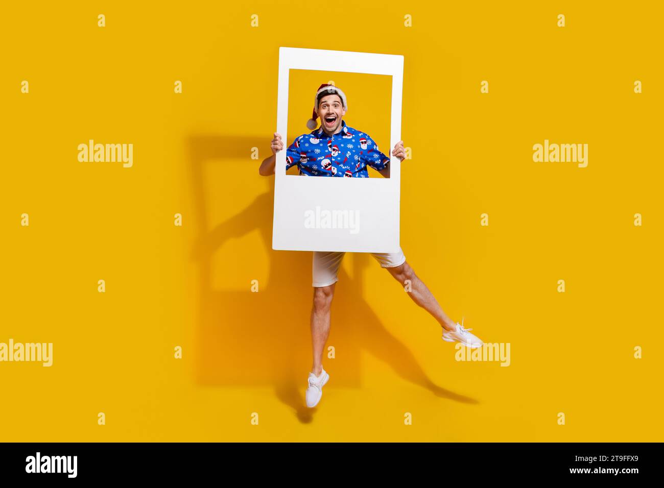 Ritratto a grandezza naturale di un affascinante ragazzo che salta le mani regge la scheda del set di album x-mas isolata su sfondo giallo Foto Stock