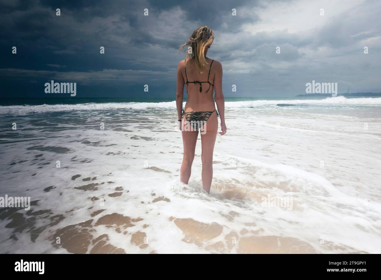 Una donna in bikini si trova sulla riva del mare sulla spiaggia di Tangalle, in Sri Lanka, in un giorno di nuvoloso Foto Stock