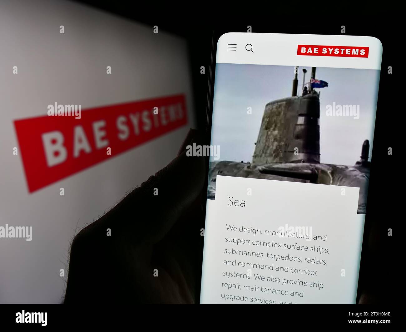 Persona che possiede un telefono cellulare con il sito Web della società britannica BAE Systems plc, azienda aerospaziale e della difesa, con logo. Concentrarsi sul centro del display del telefono. Foto Stock