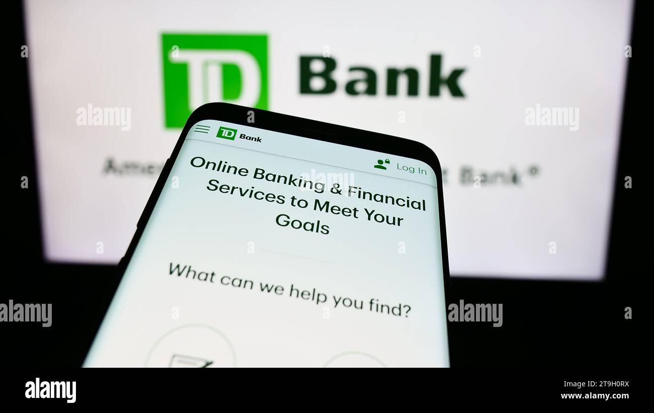 Smartphone con sito Web della società di servizi finanziari Toronto-Dominion Bank (TD) davanti al logo aziendale. Mettere a fuoco in alto a sinistra sul display del telefono. Foto Stock