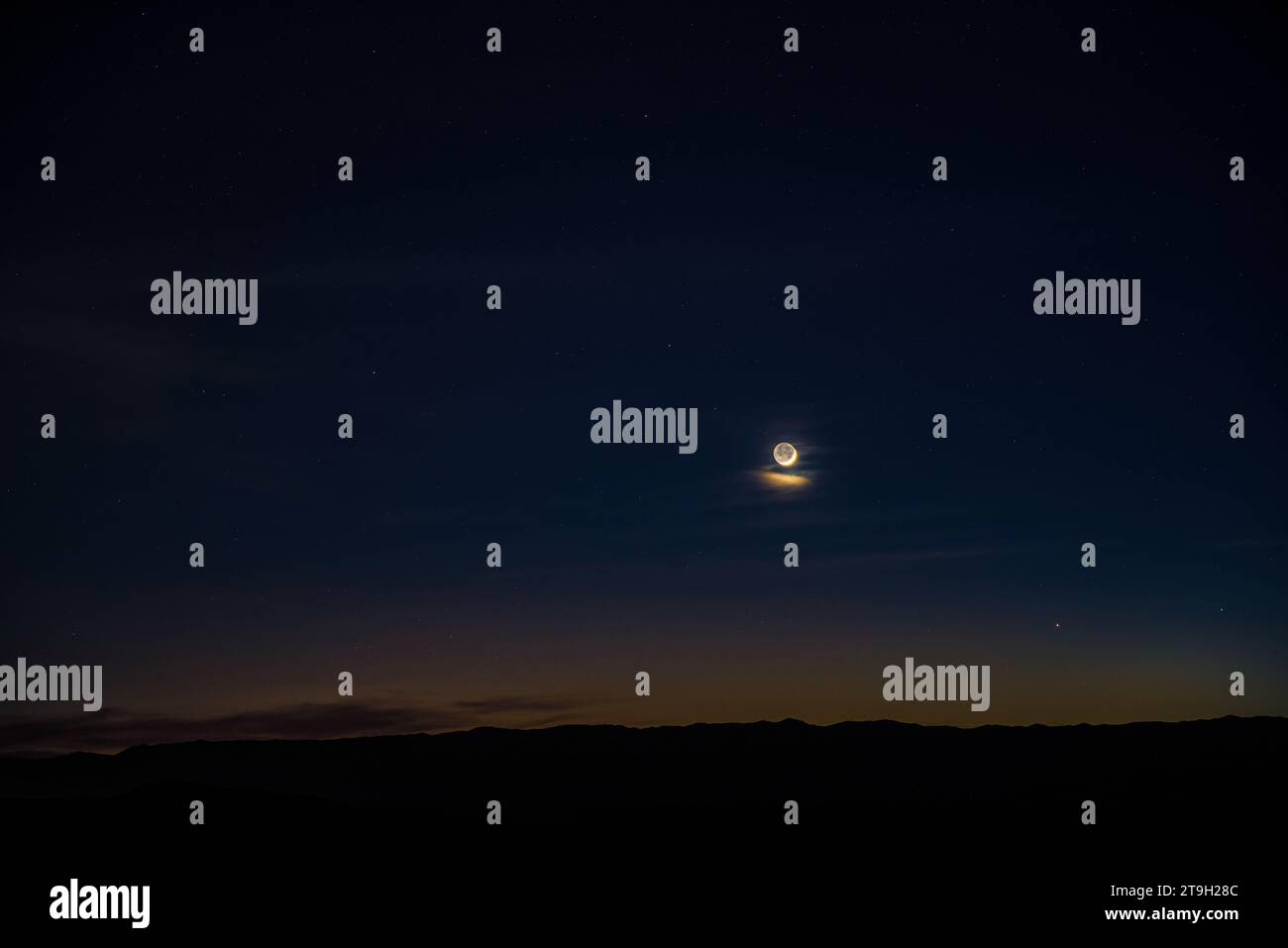 La luna mezzaluna con lucentezza di terra condivide il cielo occidentale con mercurio e Venere nel cielo del deserto riccamente colorato al crepuscolo. Foto Stock