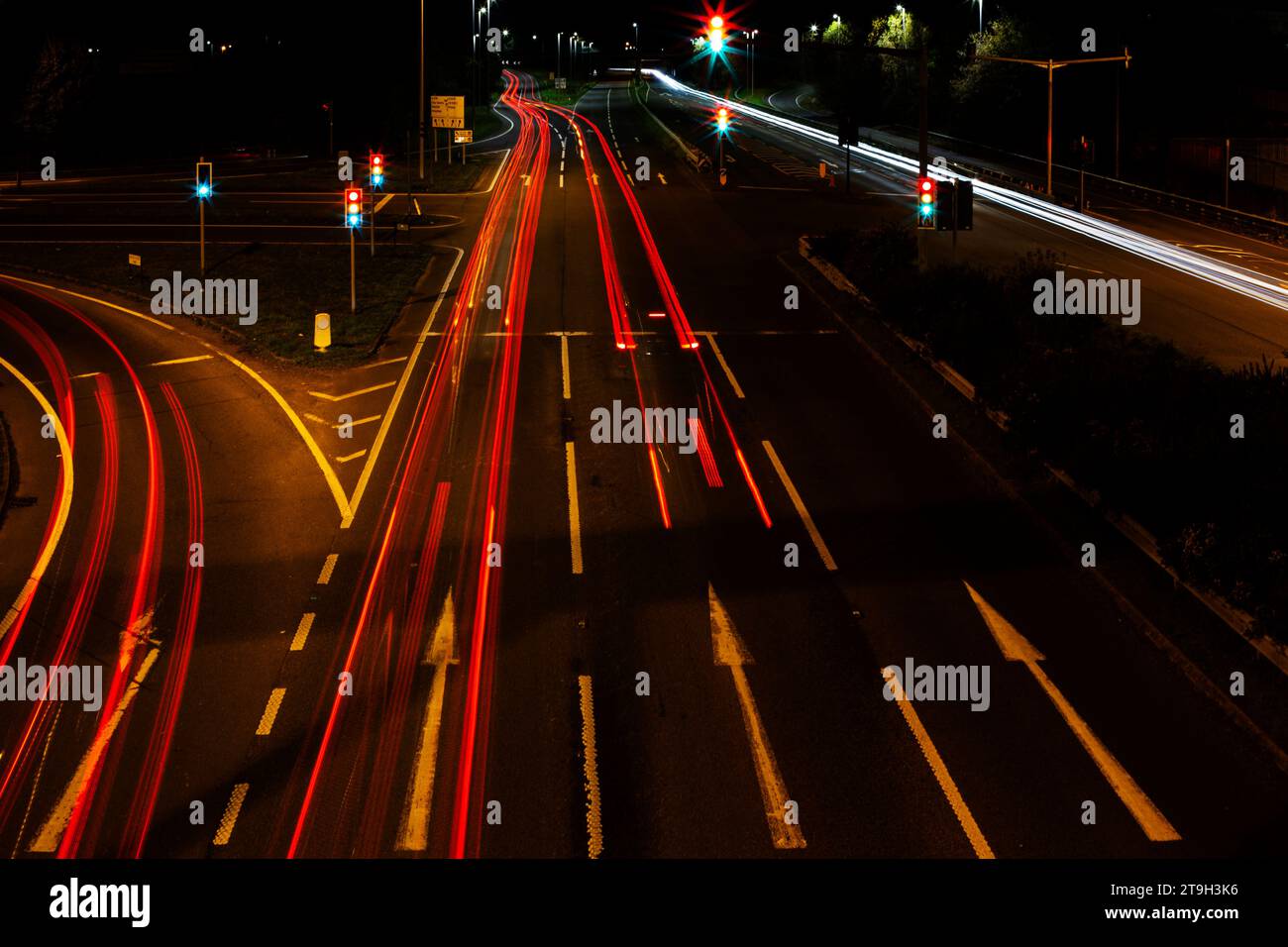 Lunga esposizione di traffico notturno presa dall'alto sul ponte che si affaccia sulla A38 vicino a Ikea a Exeter, Regno Unito Foto Stock