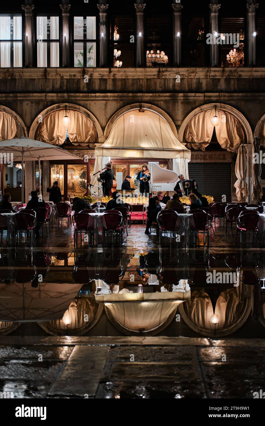 Venezia, Italia - 9 novembre 2023: Vista notturna di piazza San Marco a Venezia con persone, ristoranti e facciata illuminata Foto Stock
